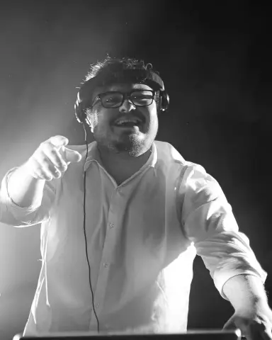 Alexandre, DJ Musse, souriant aux platines avec son casque, en noir et blanc